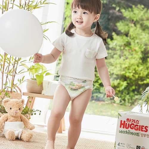 Girl Standing with Balloon and Huggies Diaper Pack