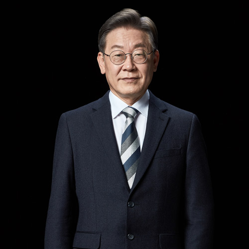 검은 배경 앞에 서서 정면을 바라보는 이재명 대통령 후보의 전신 포트레이트 A full-length front-facing portrait of presidential candidate Lee Jae-myung standing against a black background