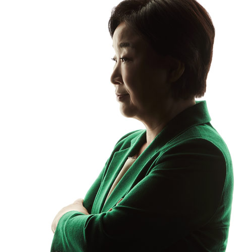 강한 백라이트 앞에서 팔짱을 끼고 옆을 바라보는 심상정 대통령 후보의 실루엣 포트레이트 A silhouette-style portrait of presidential candidate Shim Sang-jung in profile with arms crossed and backlit against a white background