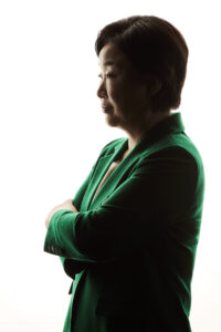 강한 백라이트 앞에서 팔짱을 끼고 옆을 바라보는 심상정 대통령 후보의 실루엣 포트레이트 A silhouette-style portrait of presidential candidate Shim Sang-jung in profile with arms crossed and backlit against a white background. Korean presidential election photo