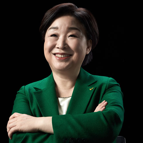 검은 배경 앞에서 팔짱을 낀 채 미소 짓는 심상정 대통령 후보의 공식 포트레이트 A confident smiling portrait of presidential candidate Shim Sang-jung with arms crossed against a black background