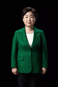 검은 배경 앞에 서 있는 심상정 대통령 후보의 공식 전신 포트레이트 A full-length front-facing portrait of presidential candidate Shim Sang-jung standing against a black background. Korean presidential election photo