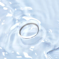 물 위에 떠 있는 렌즈미 컬러 콘택트렌즈 클로즈업 이미지 A close-up of a LensMe colored contact lens floating on clear water