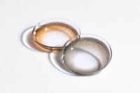 투명한 컬러 콘택트렌즈가 그림자와 함께 연출된 제품 사진 Product photo showing transparent colored contact lenses casting shadows on a white surface