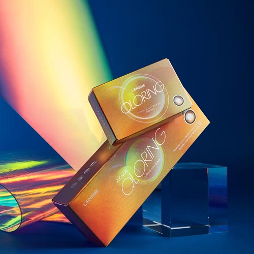 렌즈미 QLORING 콘택트렌즈 블랙 컬러 패키지와 홀로그램 배경이 어우러진 이미지 Image of LensMe QLORING contact lens boxes in black color edition, paired with rainbow holographic reflections