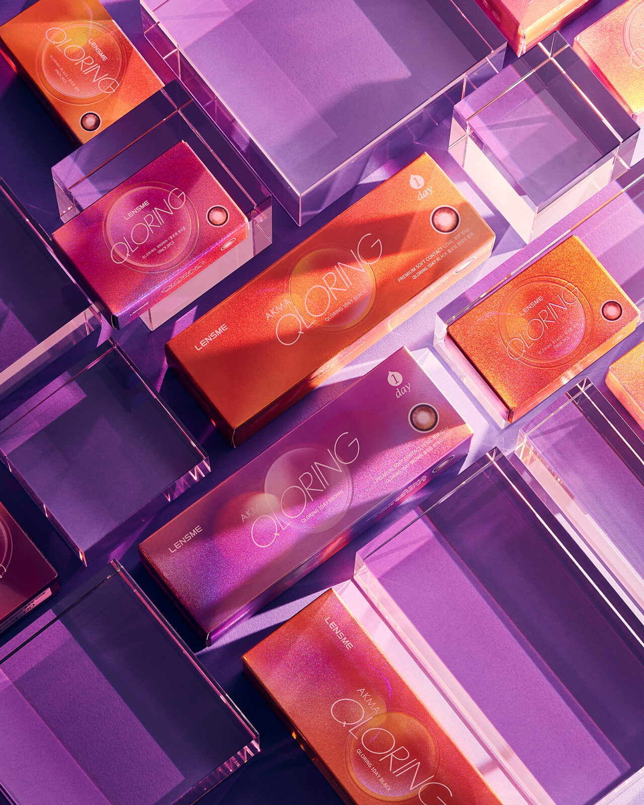 렌즈미 QLORING 콘택트렌즈 박스들이 보라색 배경 위에 배열된 이미지 Image of LensMe QLORING contact lens boxes arranged on a purple acrylic surface