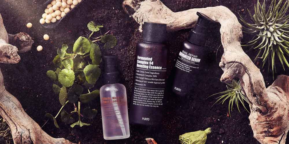 Purito Fermented Essence and Advanced Serum styled on earthy soil flatlay