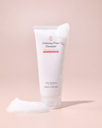 부드러운 거품과 함께 촬영된 더 하르나이 칼밍 퓨어 클렌저 Calming cleanser tube with water droplets and soft foam on pink background