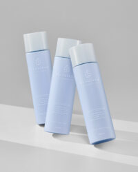 히줄렌 콜라겐 로션 3개가 회색 배경 위에 세워져 정렬된 모습 Three Hyzulene collagen lotion bottles arranged upright on a soft gray background