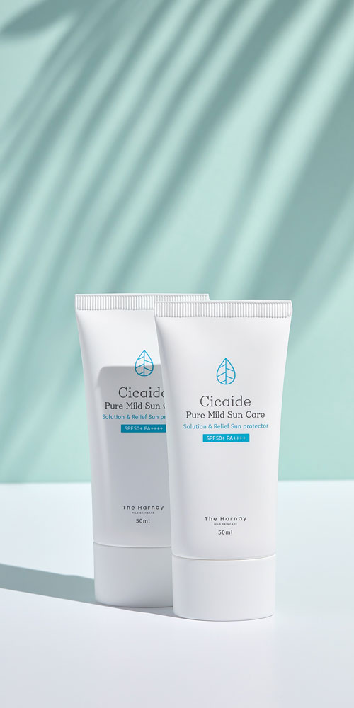 야자수 그림자 아래 놓인 시카이드 순한 자외선 차단제 2종 Cicaide sunblock products under palm leaf shadows on mint blue background