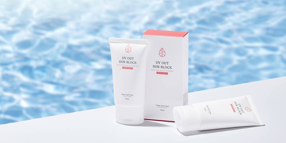 수영장을 배경으로 더 하르나이 UV OUT 톤업 선크림 제품이 배치된 장면 Tone-up sunblock product styled with a pool water backdrop