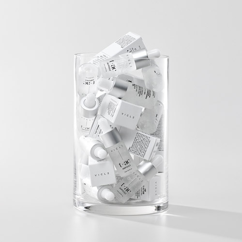 Vicle 앰플 제품과 박스를 유리 실린더 안에 가득 채워 촬영한 장면 A glass cylinder filled with Vicle ampoules and their boxes in a stacked composition