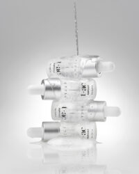 투명 앰플 병 여러 개를 수직으로 쌓고 위에서 액체를 붓는 장면 Vicle ampoule bottles stacked – commercial skincare photography . Several Vicle ampoules stacked vertically while water is poured over them
