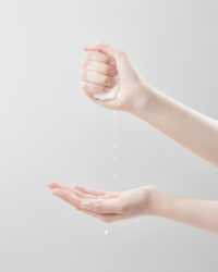 한 손으로 적신 패드를 꽉 쥐고 다른 손바닥 위로 물방울이 떨어지는 장면 Foam texture dripping in hand – Vicle skincare product shot . A soaked cotton pad squeezed in one hand as water drips into the other