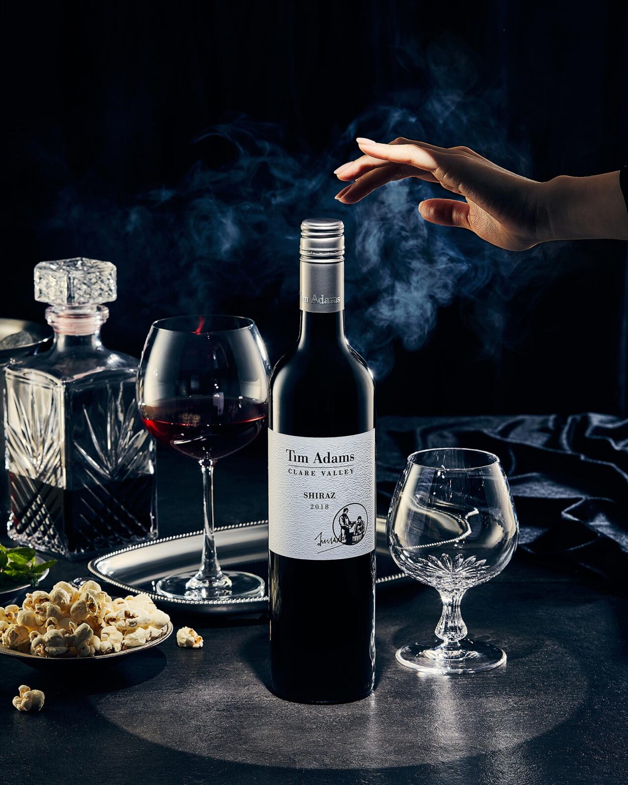어두운 배경과 연기 속에 손이 와인병을 향해 뻗은 연출 이미지 A dramatic scene of a hand reaching toward a wine bottle surrounded by smoke and deep shadows