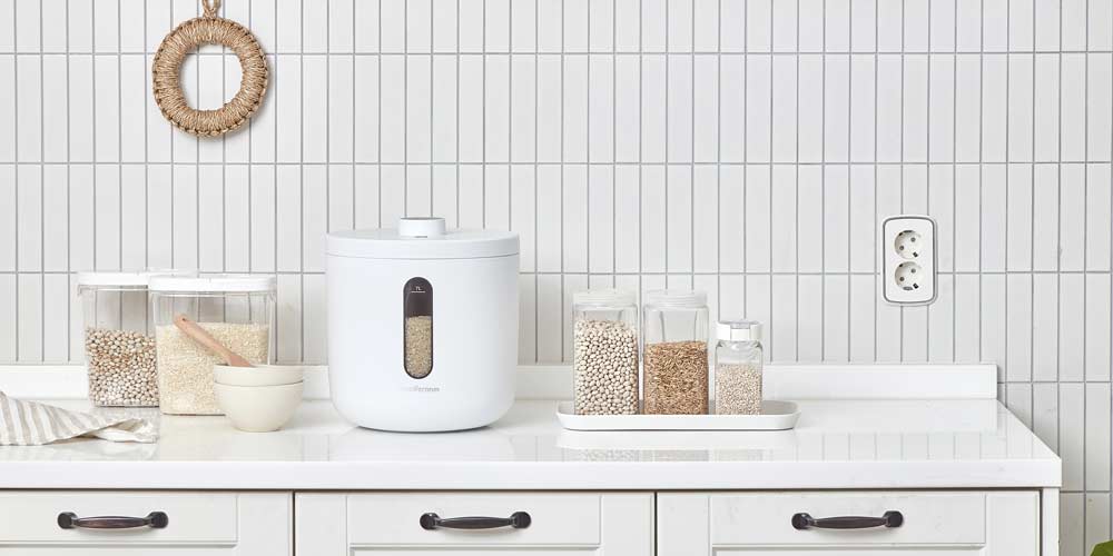 화이트 제니퍼룸 쌀통과 다양한 곡물 보관 용기가 주방에 배치된 모습 Product photo of white Jenniferroom rice container with various grain storage jars in a kitchen setting