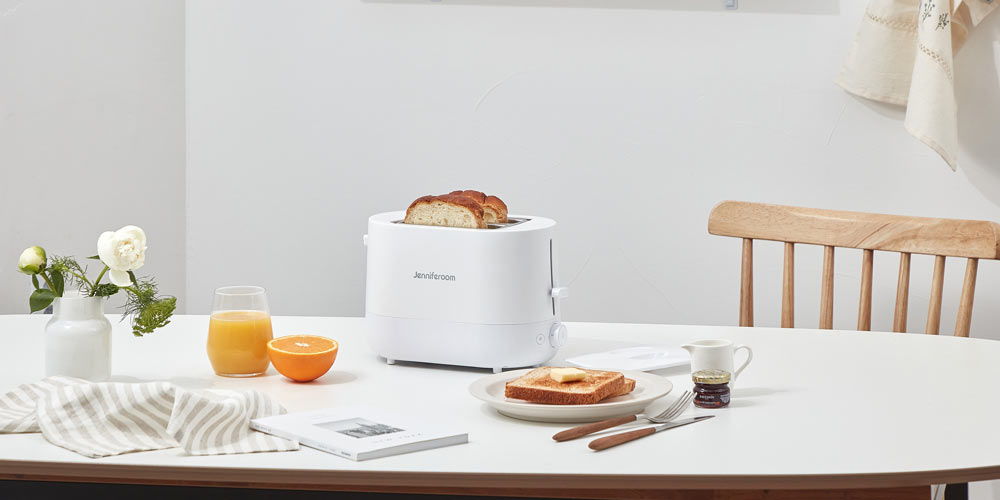 화이트 제니퍼룸 토스터와 빵, 주스, 버터가 놓인 아침 식사 테이블 Product shot of Jenniferroom white toaster with bread, juice, and butter on breakfast table