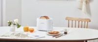 화이트 제니퍼룸 토스터와 빵, 주스, 버터가 놓인 아침 식사 테이블 Product shot of Jenniferroom white toaster with bread, juice, and butter on breakfast table