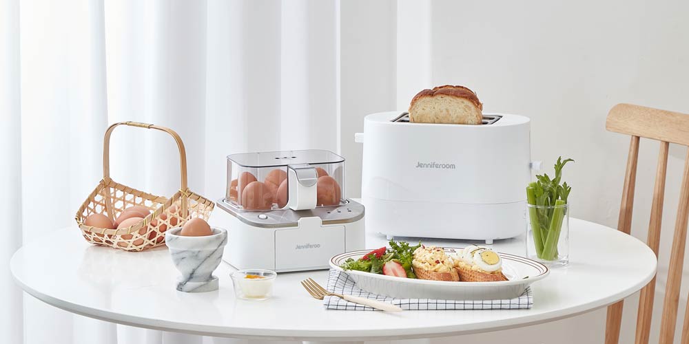 화이트 제니퍼룸 토스터와 에그쿠커, 달걀 요리, 샐러드, 식빵이 놓인 아침 식사 테이블 Product shot of Jenniferroom white toaster and egg cooker with breakfast setting