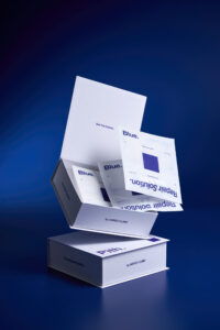 블루리페어 화이트 박스가 열리며 시트마스크 파우치들이 흘러나오는 제품 사진 Packshot showing the Blue Repair box opened with multiple sheet mask pouches flowing out in dynamic arrangement