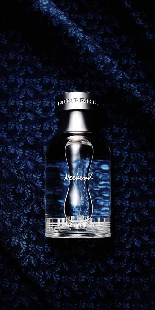 버버리 위크엔드 향수 병이 짙은 네이비 천 위에 놓여 있는 제품 사진 Burberry Weekend perfume bottle placed on dark navy textured fabric