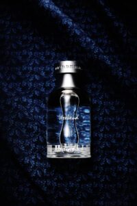 버버리 위크엔드 향수 병이 짙은 네이비 천 위에 놓여 있는 제품 사진 Burberry Weekend perfume bottle placed on dark navy textured fabric