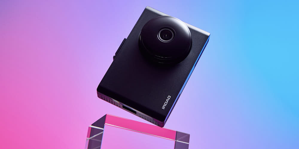 네온 핑크와 블루 조명이 비추는 무드 속의 아이로드 블랙박스 제품 사진 Photo of IROAD dashcam in vibrant neon pink and blue lighting, highlighting modern style