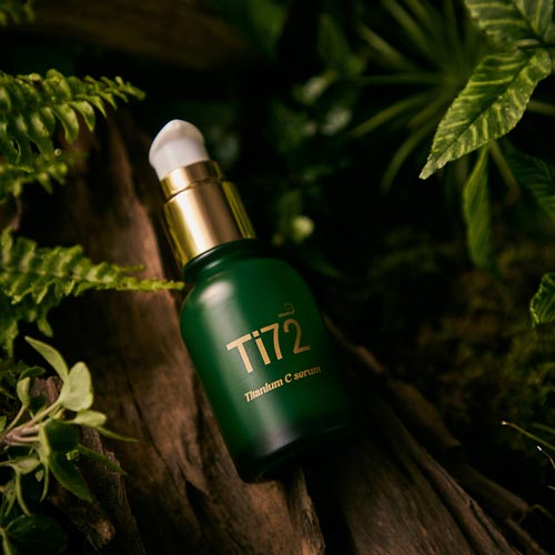 숲 속 배경 위에 놓인 휴메디컬 Ti72 세럼 병 제품 사진 Product photo of Humedical Ti72 Titanium C Serum bottle placed in a natural forest background