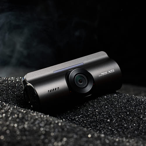 블랙 텍스처 위에 배치된 아이로드 X6 블랙박스 제품 사진 IROAD X6 dashcam placed on black sand textured surface
