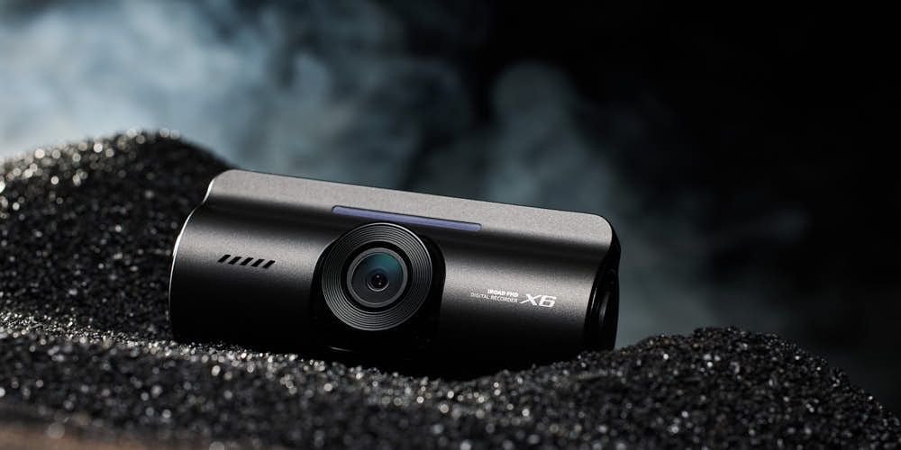 블랙 텍스처 배경에 놓인 아이로드 X6 블랙박스 제품 이미지 IROAD X6 dashcam product on black textured surface
