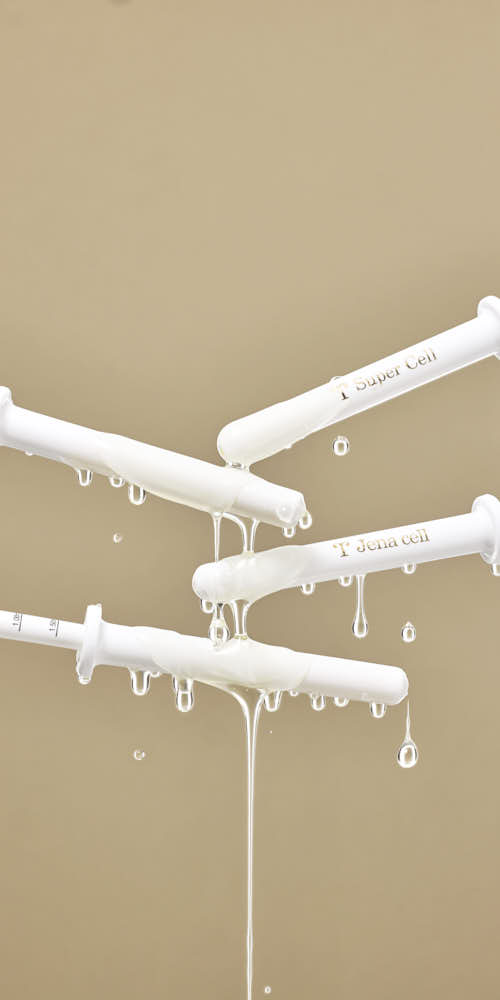 제나셀 세럼 주사기에서 흐르는 금빛 제형 클로즈업 사진 Close-up shot of JenaCell serum syringe with golden liquid flowing, styled in a lab-inspired concept