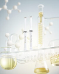 실험실 배경 속 금빛 제형과 함께 연출된 제나셀 시그니처 주사기형 세럼 제품 사진 Jenacell syringe-type serum photographed with laboratory objects and golden-toned liquids, highlighting premium skincare identity