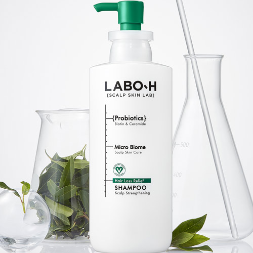 LABO-H 탈모 완화 샴푸 병이 유리 비커와 식물과 함께 연출된 제품 이미지 LABO-H hair loss relief shampoo bottle styled with glass beakers and green leaves